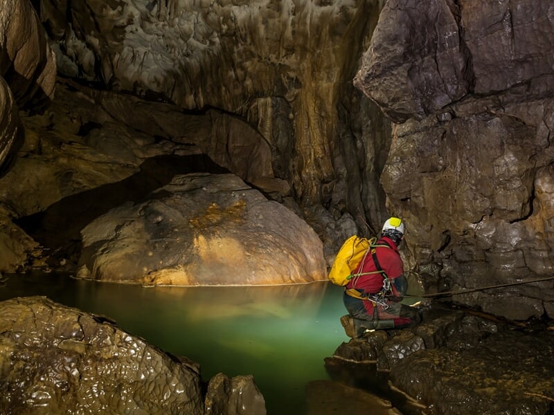 Personne dans une grotte avec point d'eau sous-terrain