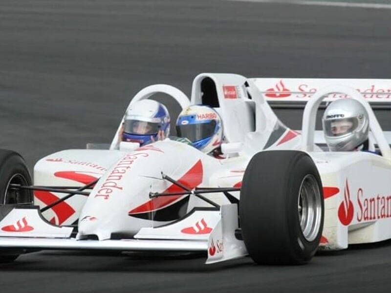 une formule 1 blanche triplace en pleine course sur une piste