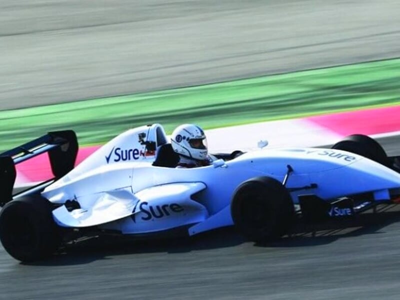une formule renault blanche en pleine course sur un circuit asphalte