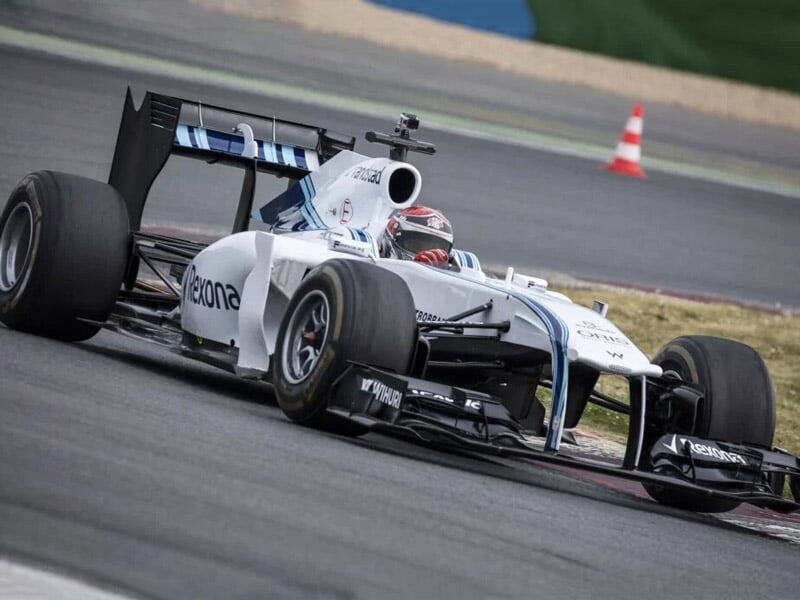 une formule 1 blanche en plein virage sur une piste asphalte