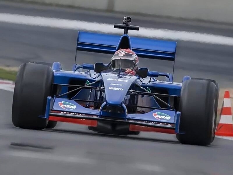 une formule 1 bleue de face sur une piste de course