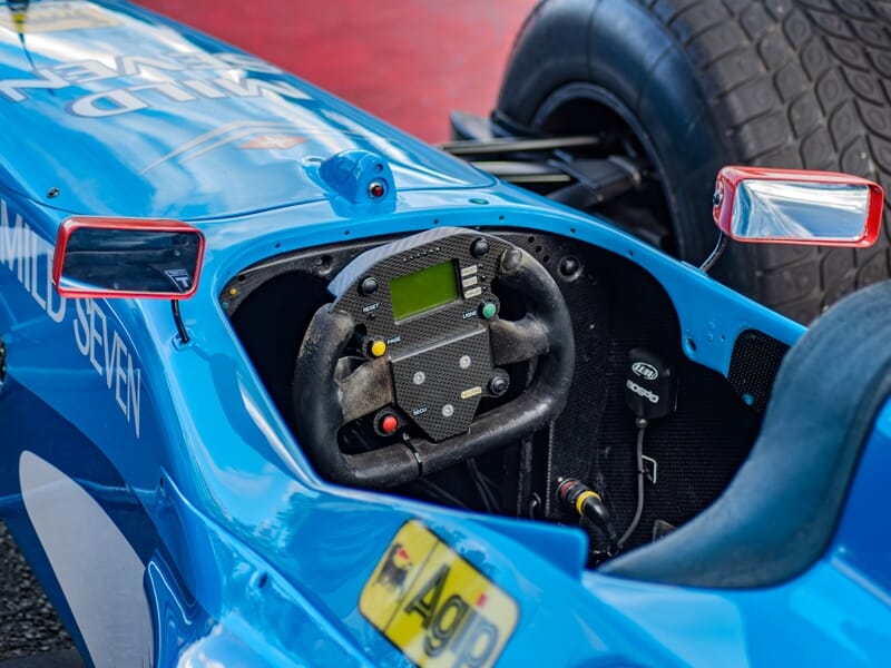 Gros plan sur le volant et le cockpit d'une voiture de Formule 1 bleue prête à piloter.