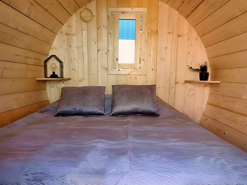 Intérieur d'une petite chambre en bois avec un lit double, lors d'un séjour insolite dans la Baie de Somme.