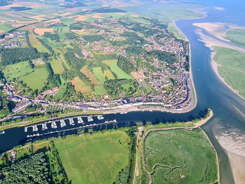 Vue aérienne d'Abbeville avec ses maisons, un port de plaisance, des champs verts lors d'un séjour insolite dans la Baie de Somme.