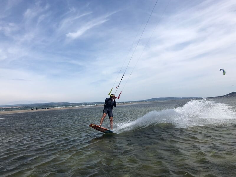 Une personne en train de faire du kitesurf, provoquant une vague derrière elle