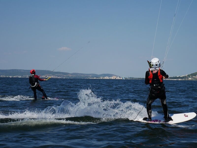 Deux personnes en train de faire du kitesurf, le ciel bleu en fond