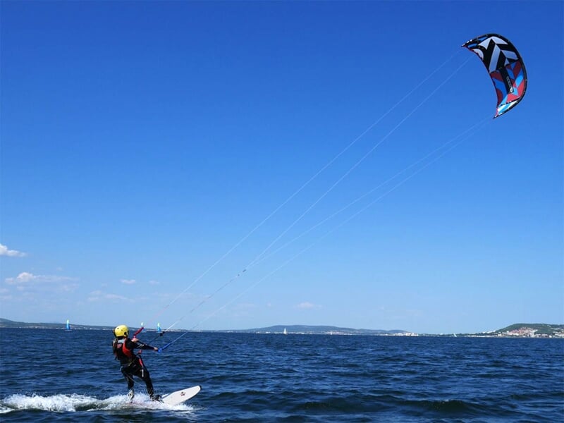 Une personne en train de faire du kitesurf, avec le ciel bleu en fond