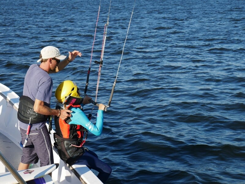 Deux personnes au bord d'un bateau, l'une prête à l'élancer avec son kitesurf