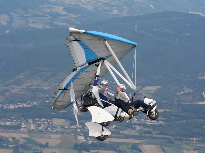 Deux personnes en vol sur un ULM biplace blanc et bleu lors d'un baptême de l'air en ULM près de Dijon.