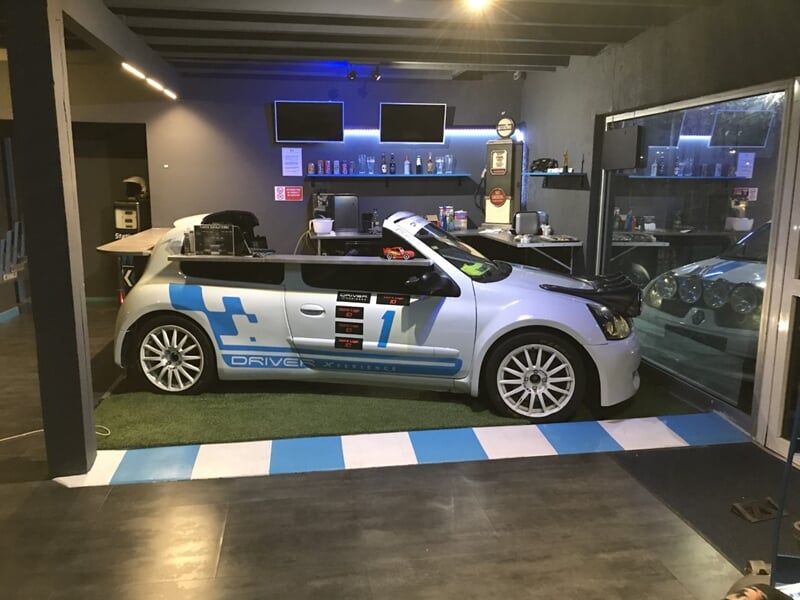 Voiture de course blanche avec logos bleus exposée dans un espace intérieur moderne et lumineux.