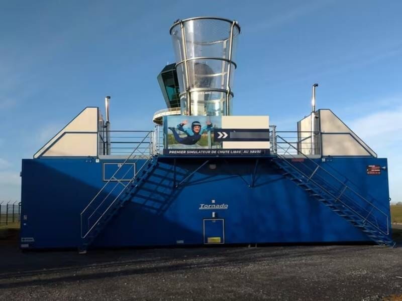 Simulateur de chute libre « Tornado » sur structure bleue avec tube central transparent.