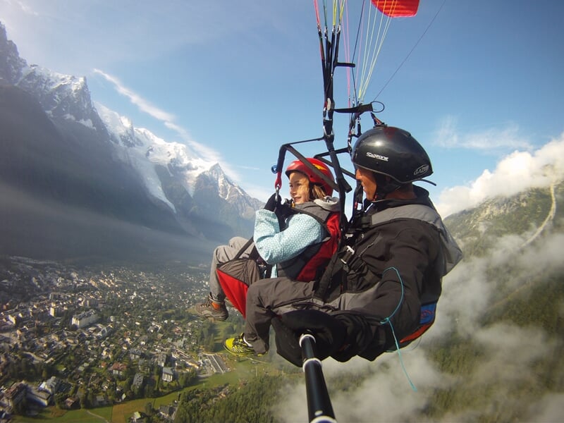Vol en tandem de parapente au-dessus de Chamonix avec vue sur la ville et les montagnes enneigées.