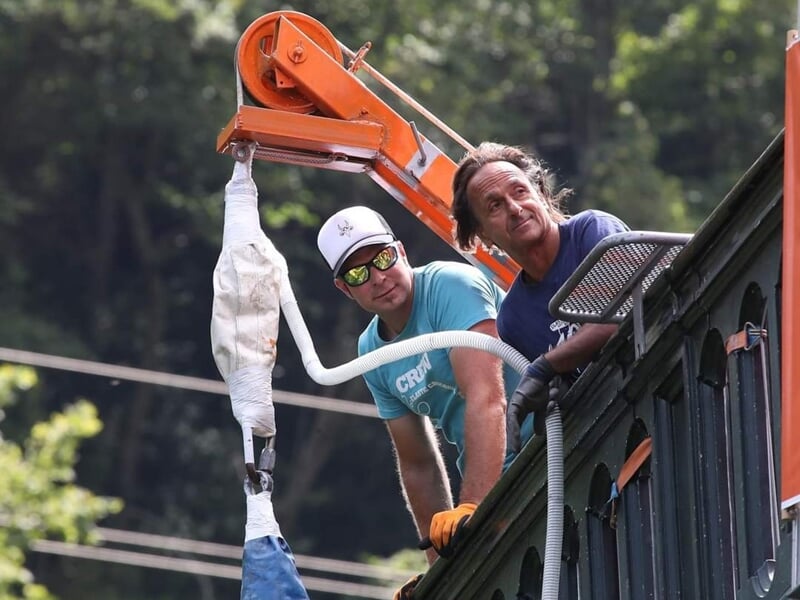 Deux hommes sur une plateforme, l'un portant un casque et des lunettes, préparant un saut à l'élastique.