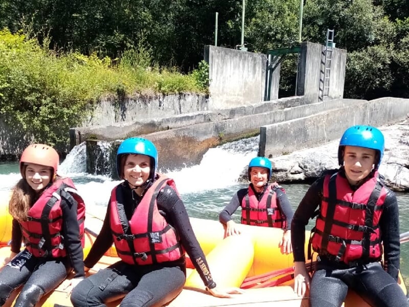 Rafting en rivière avec plusieurs personnes en gilets de sauvetage rouges pagayant dans des rapides.