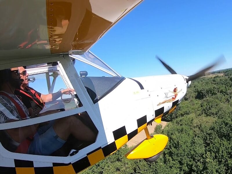 Pilote dans un petit avion léger volant au-dessus d'une forêt dense par une journée ensoleillée.