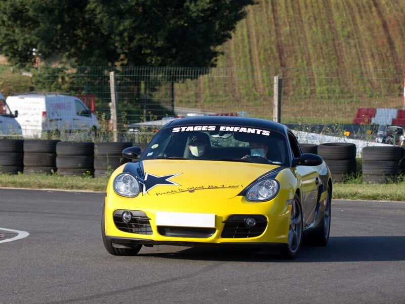 Voiture de sport jaune avec toit noir sur une piste de course, marquée