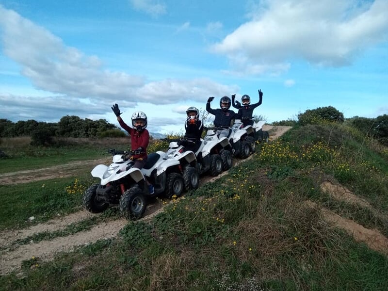 Quatre personnes sur des quads blancs sur une colline herbeuse, levant les bras en signe de joie.