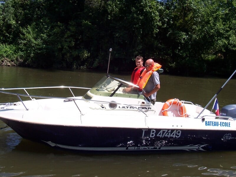 Deux hommes sur un bateau-école blanc naviguant sur une rivière entourée d'arbres verts en été