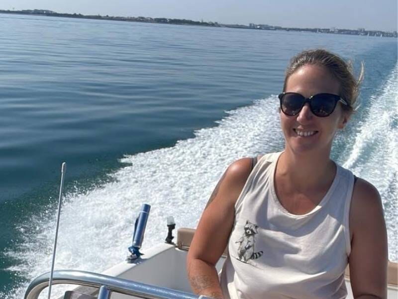 Une femme souriante aux commandes d'un bateau lancé à vive allure.