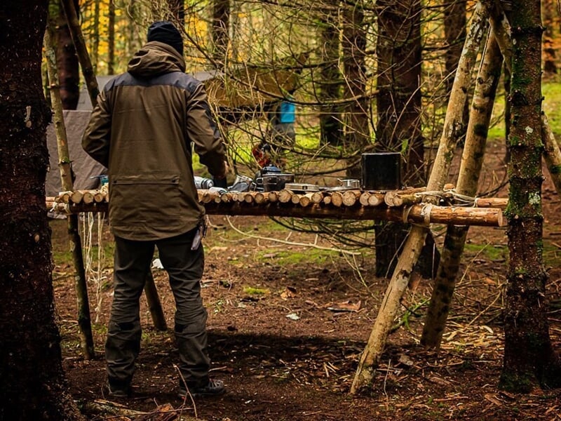 un homme entrepose des objets sur une table de bois de fortune
