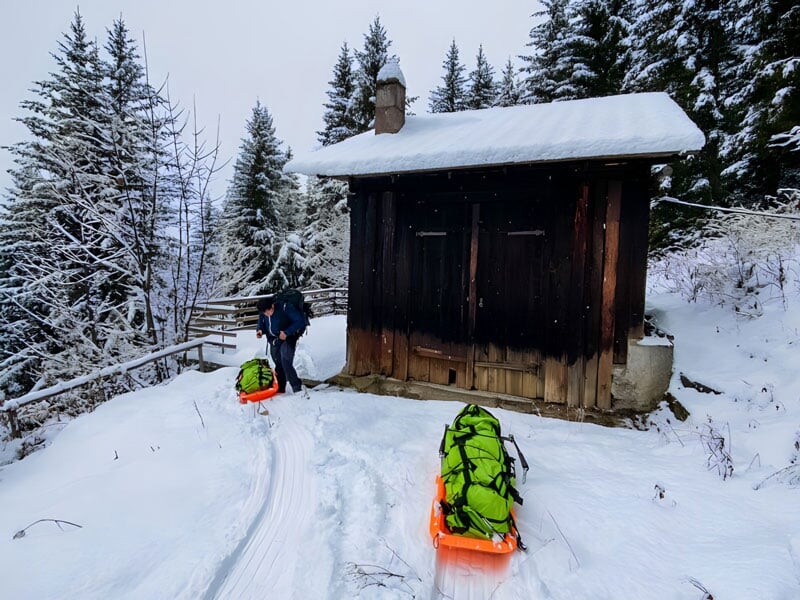 une pulka chargée devant une cabane en bois