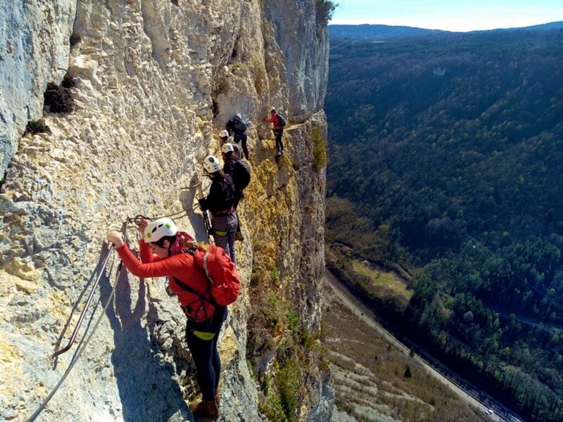 des personnes longent une falaise en via ferrata