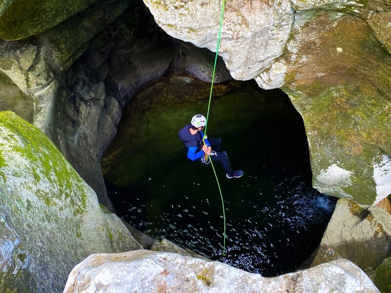 une personne descend en rappel dans un puits naturel