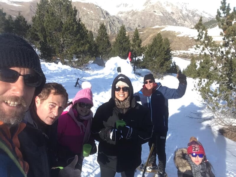 Groupe de six personnes en tenue d'hiver, souriantes, posant pour une photo en pleine nature enneigée.