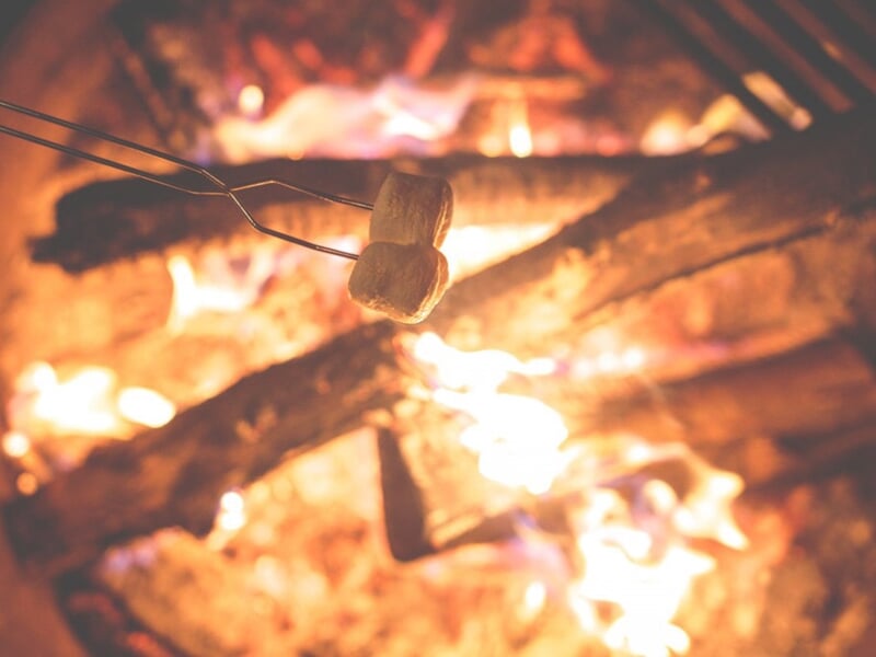 Marshmallow en train de griller sur un feu de camp avec des flammes et des braises