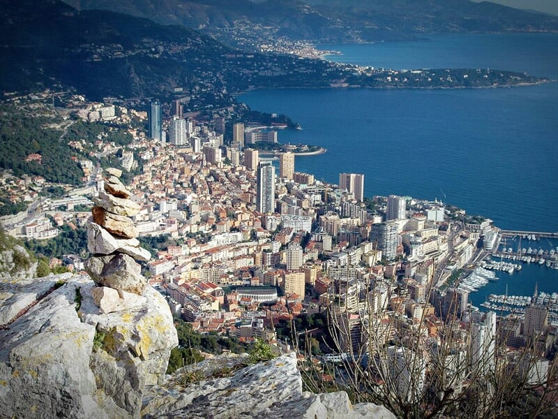 Vue aérienne d'une ville dense avec des immeubles, un port et la mer en arrière-plan sous un ciel clair