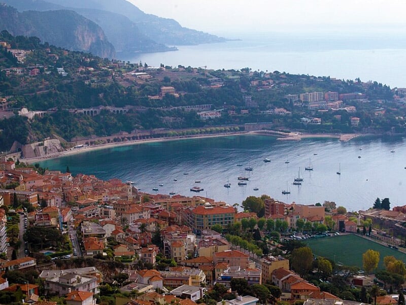 Vue panoramique d'une baie avec une ville en bord de mer, des collines et des bateaux au port