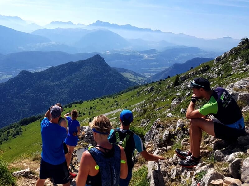 Groupe de coureurs de trail en montagne observant le paysage depuis un point élevé avec vue sur la vallée