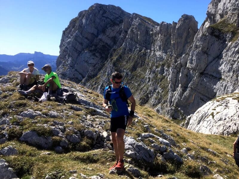 Coureurs de trail en pause sur un sommet rocheux avec des montagnes imposantes en arrière-plan