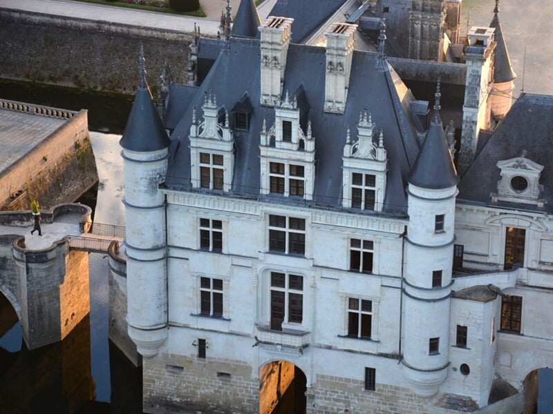 Château de style Renaissance avec des tourelles et des façades ornées, entouré de douves remplies d'eau, vue aérienne