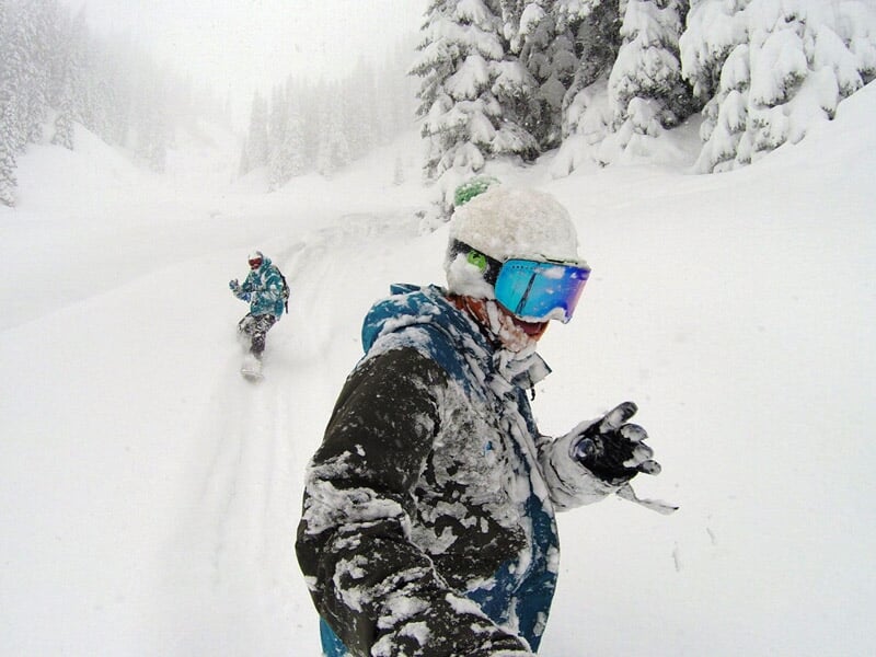 Skieur en tenue d'hiver avec lunettes de protection dans une forêt enneigée lors d'une randonnée en ski.