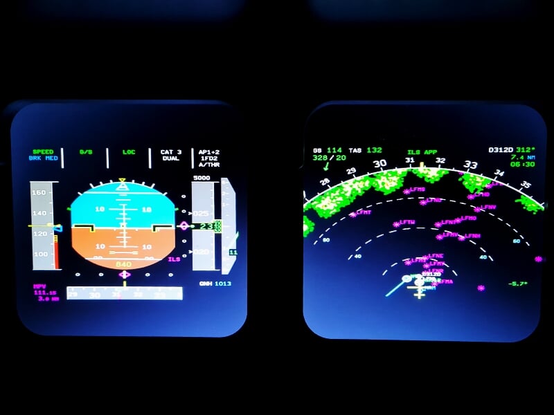 Écrans d'instruments de vol dans un simulateur d'avion affichant données de navigation et radar.