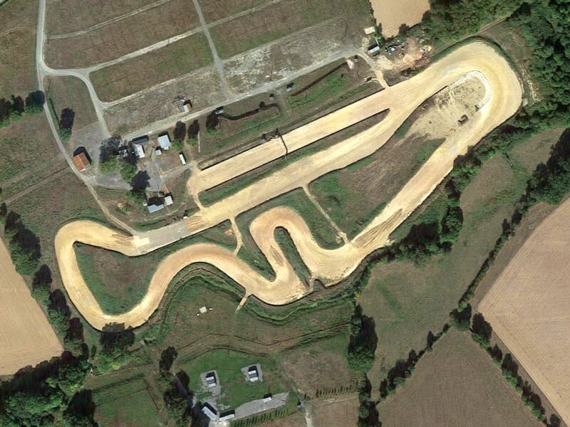 Vue aérienne d'un circuit de rallye terre avec des virages en épingle et des chemins adjacents.