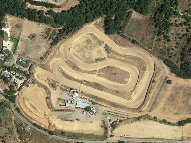 Vue aérienne d'un circuit de rallye terre avec plusieurs virages serrés et zones dégagées.
