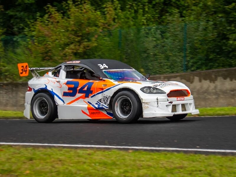 Voiture mitjet blanche, orange et bleu sur une piste.