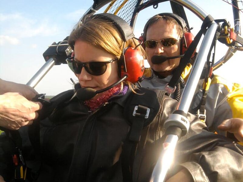 Femme et homme en vol en paramoteur, portant casque et casque audio, concentrés.