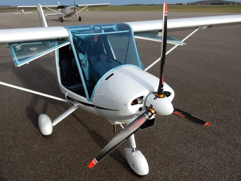 Avion ULM blanc stationné sur l'aérodrome de Nancy Essey avec hélice et cockpit visible de face.