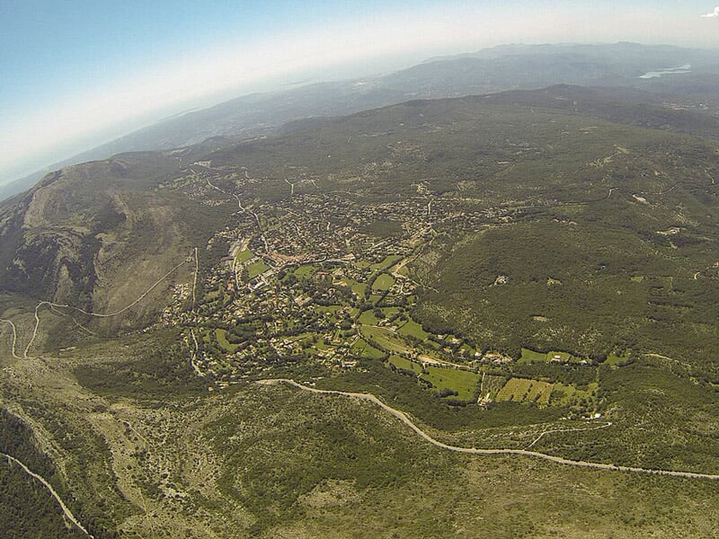 Paysage vu du ciel montrant une vaste étendue de collines et de forêts sous un ciel dégagé.