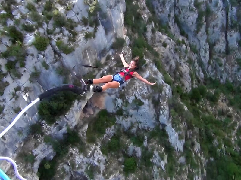 Une jeune femme en short en plein vol lors d'un saut à l'élastique au pont de l'Artuby