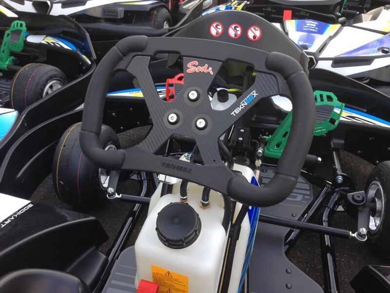 Gros plan sur le volant et le réservoir d'un karting noir et blanc avec des détails verts et rouges.