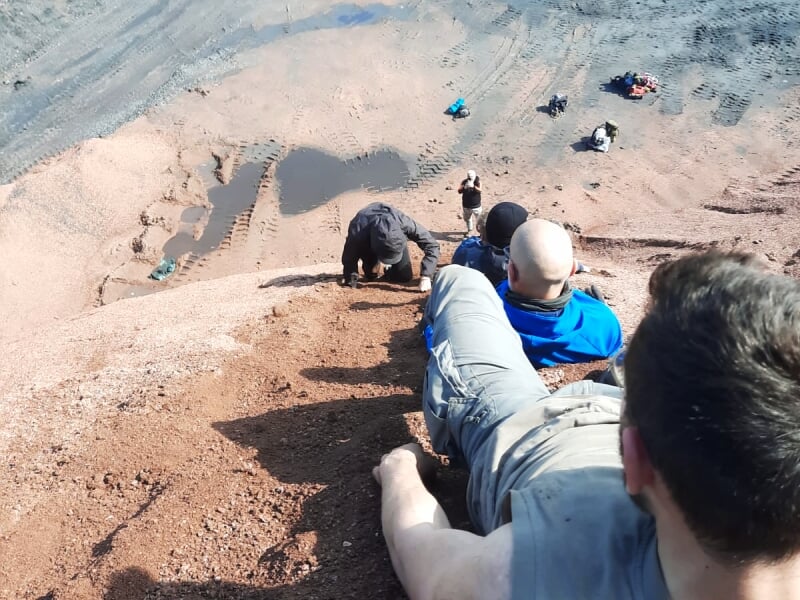 Personnes descendant une pente raide et rocheuse lors d'une activité sportive extrême.