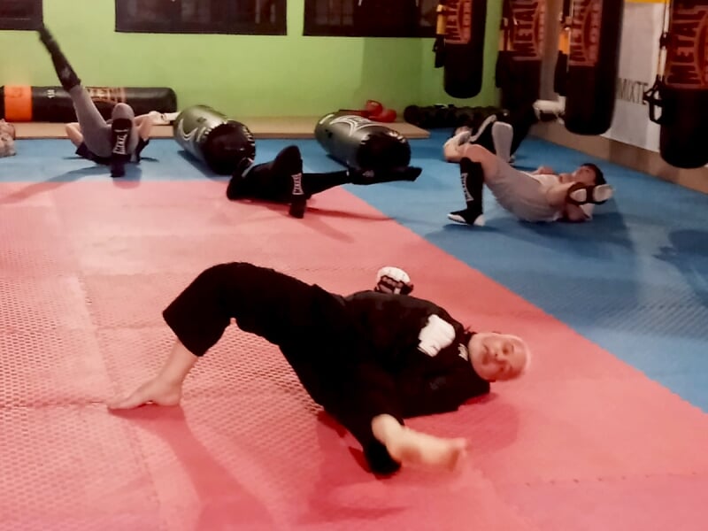 Groupe de personnes allongées sur un tapis bleu, pratiquant des exercices de relaxation ou étirement.