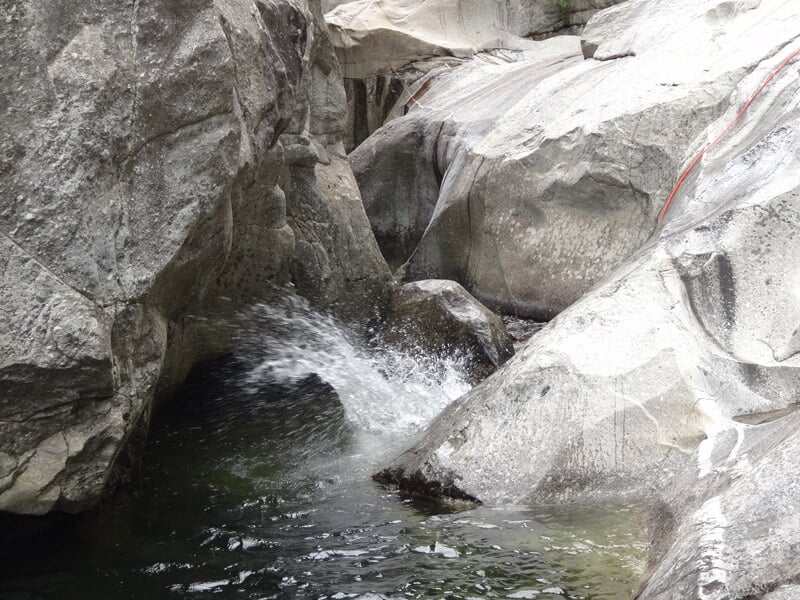 Paysage naturel de canyon avec eau claire et rochers lisses formant un bassin d'eau calme.