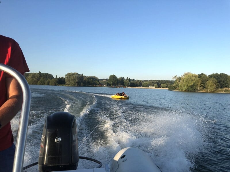 Vue depuis un bateau motorisé sur un lac avec une bouée tractée jaune à l'arrière en mouvement.