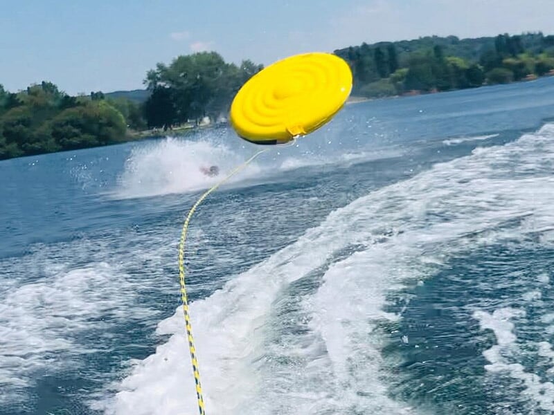 Bouée jaune tractée par un bateau, projetée en l'air avec éclaboussures sur un lac.