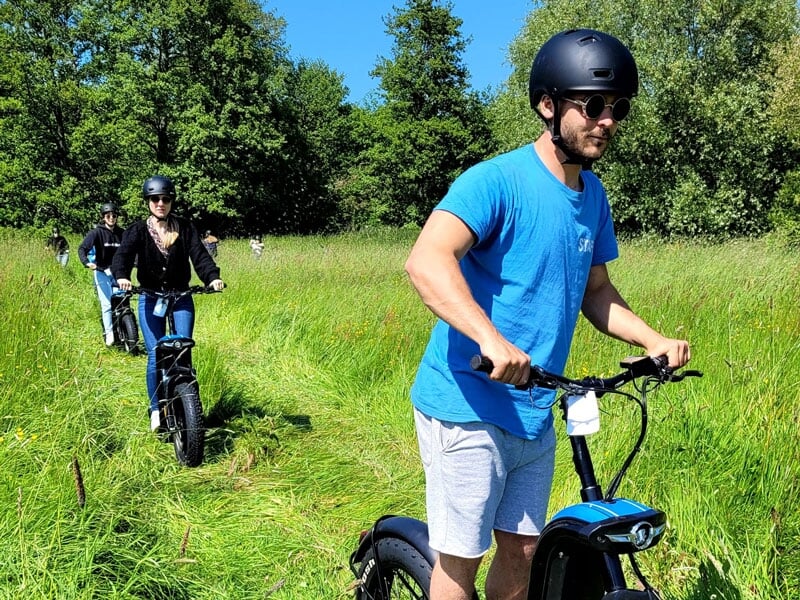 Un groupe traverse une prairie en trottinette électrique